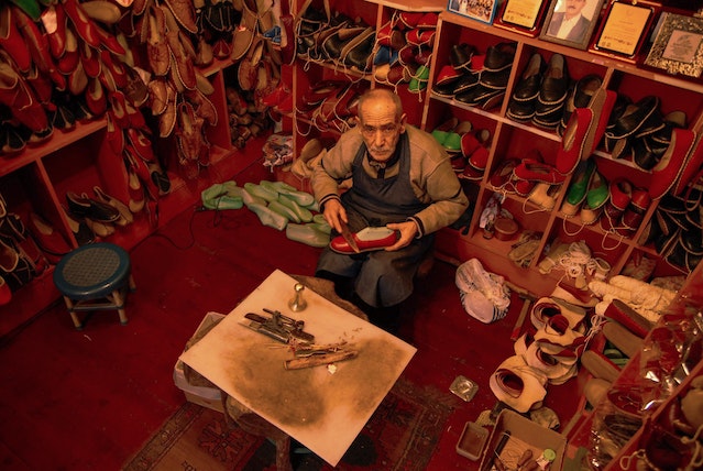 Oude ambachtelijke schoenmaker die een schoen repareert 